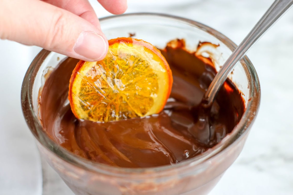 dipping orange slices into chocolate