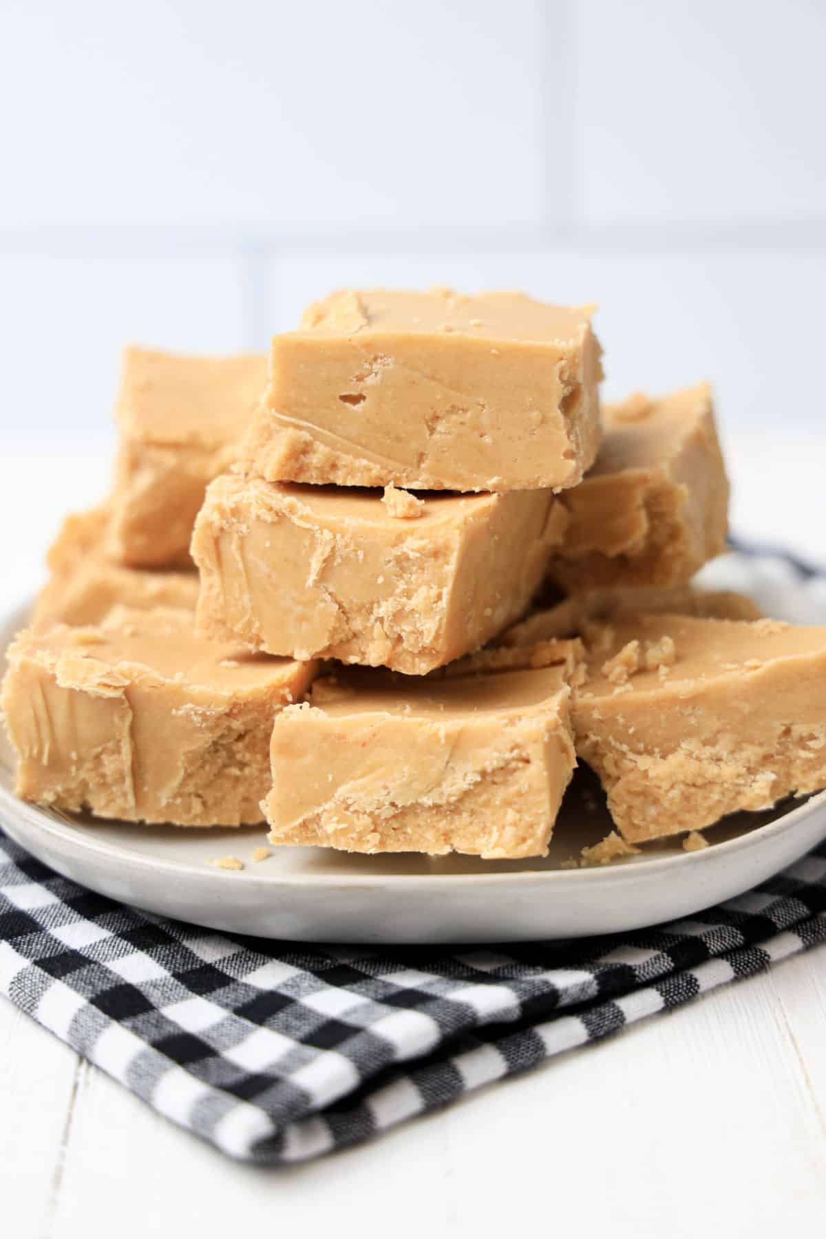 stack of peanut butter fudge on white plate with black and white napkin