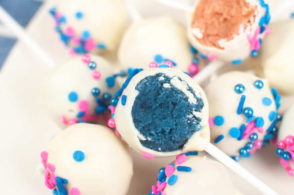 gender reveal cake pops with white coating and sprinkles, ble and pink in center