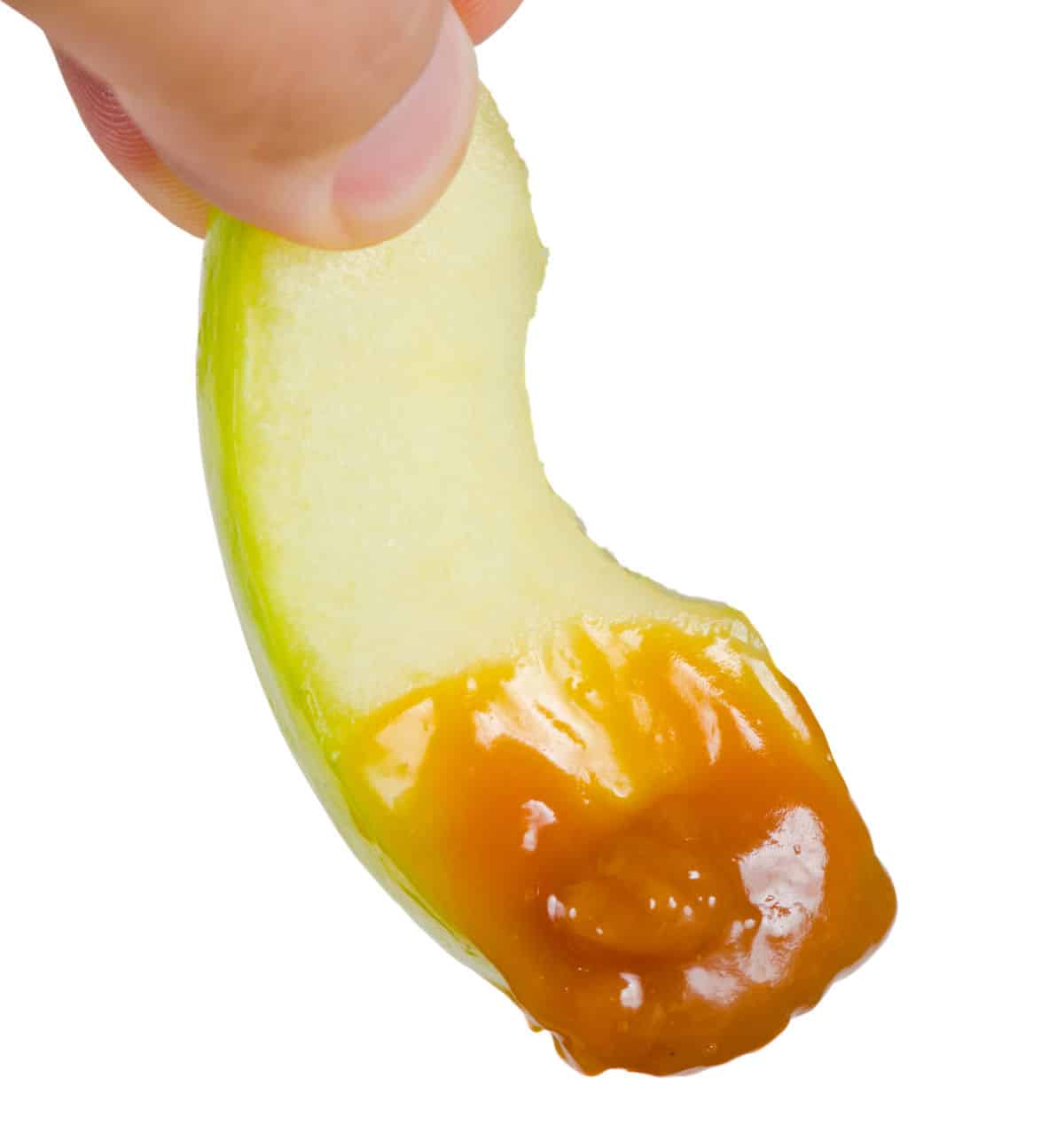 apple slice dipped in caramel  held by fingers