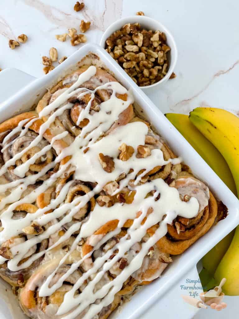 banana nut cinnamon rolls in pan with bananas on side
