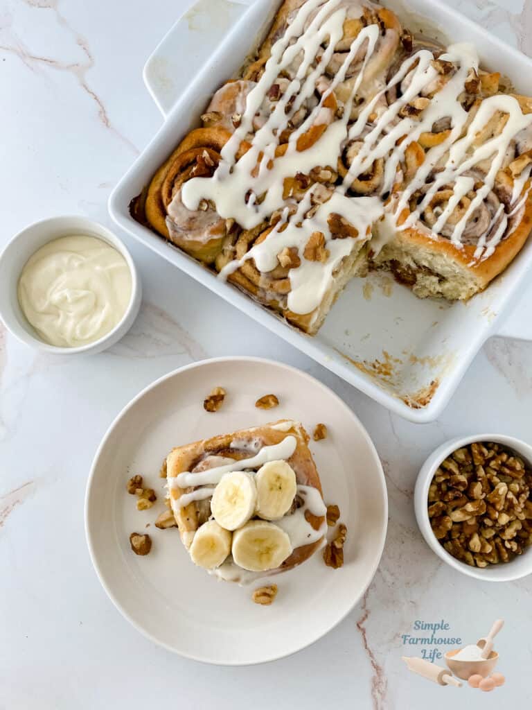 banana cinnamon rolls in pan and one on a white plate with nuts on the side