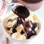chocolate dipping sauce on vanilla ice cream in bowl with spoon drizzling the chocolate