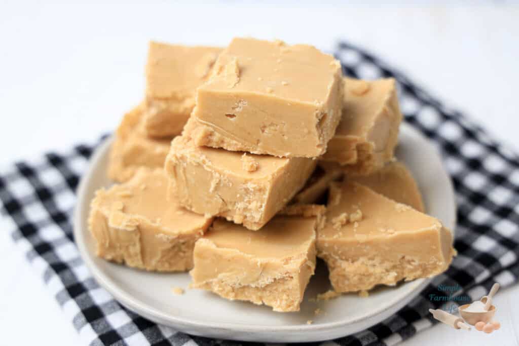 peanut butter fudge pieces stacked on white plate with black checked napkin
