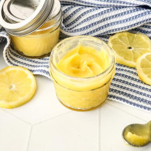 homemade lemon curd in small jar with blue striped towel