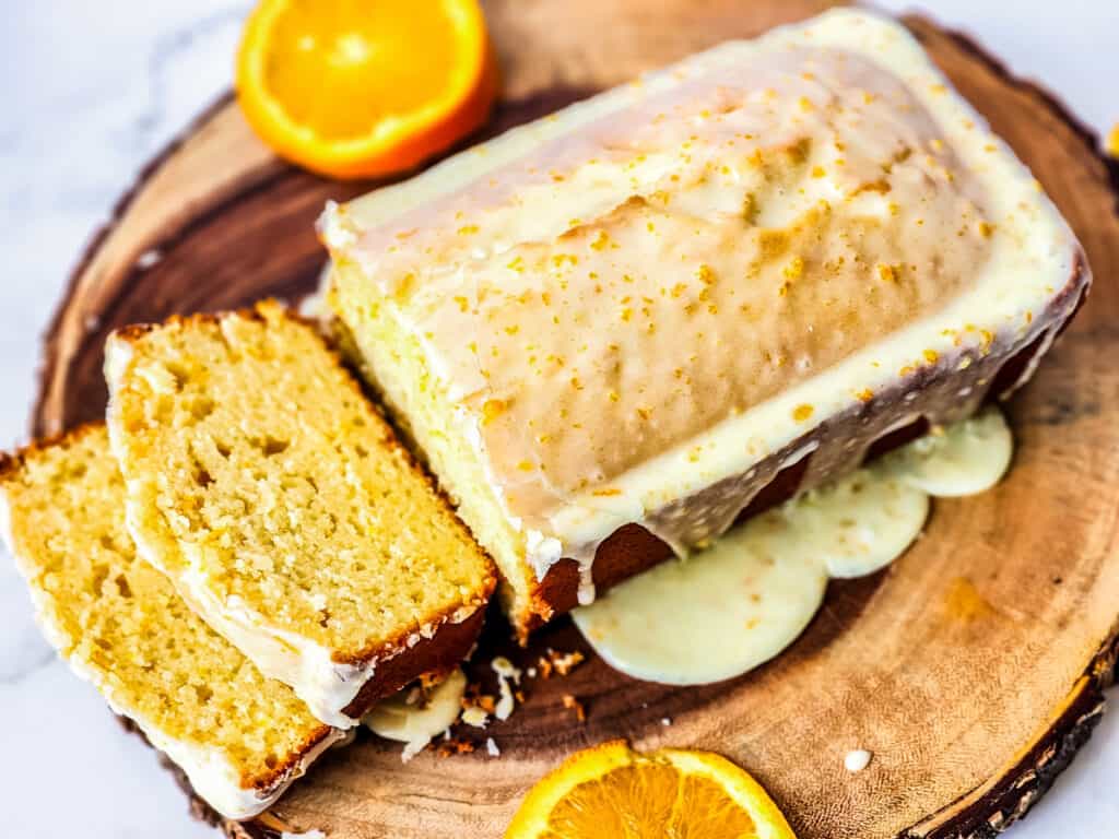 orange loaf cake with slices on round wood bosrd